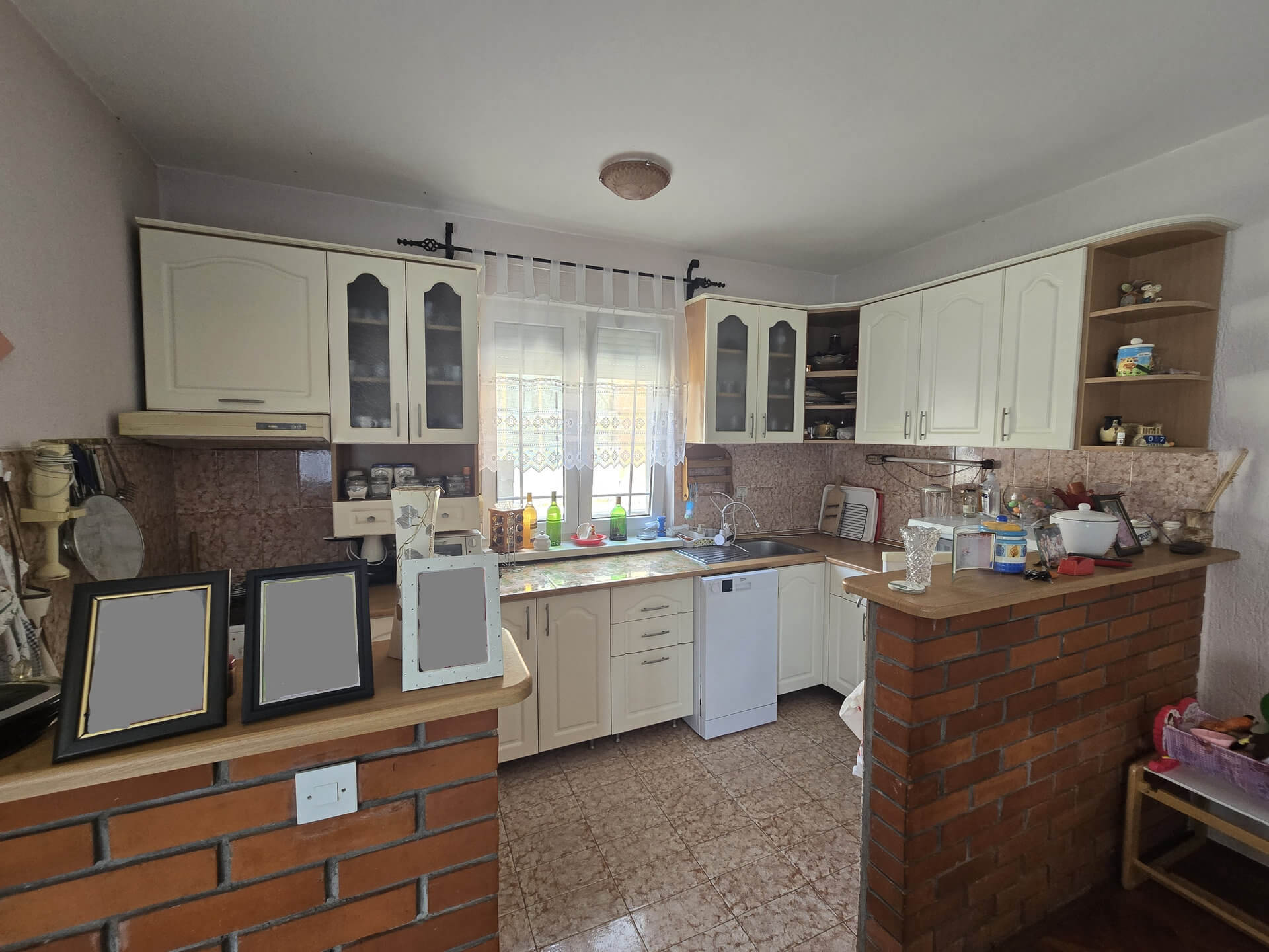 Velika bela kuhinja, mašina za pranje suđa, prozor u kuhinji