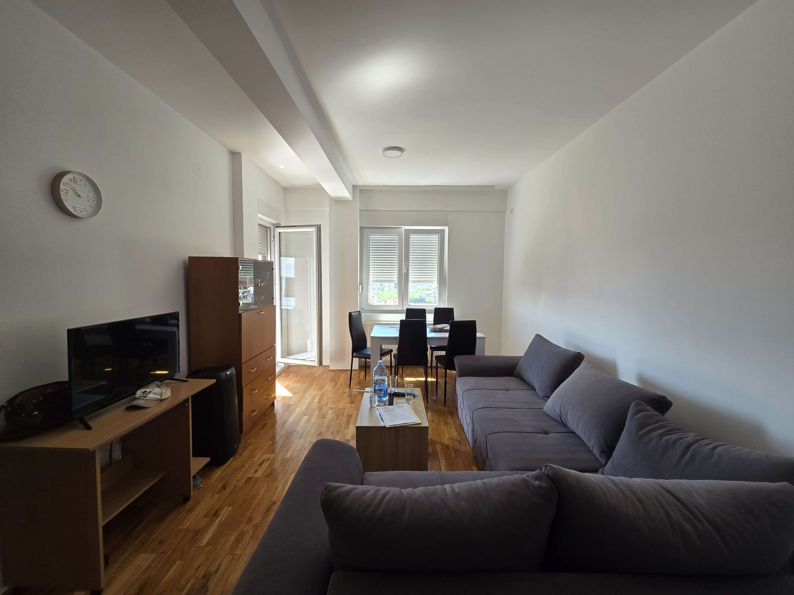 Dnevna soba, levo je komoda sa tv, regal i izlaz na terasu