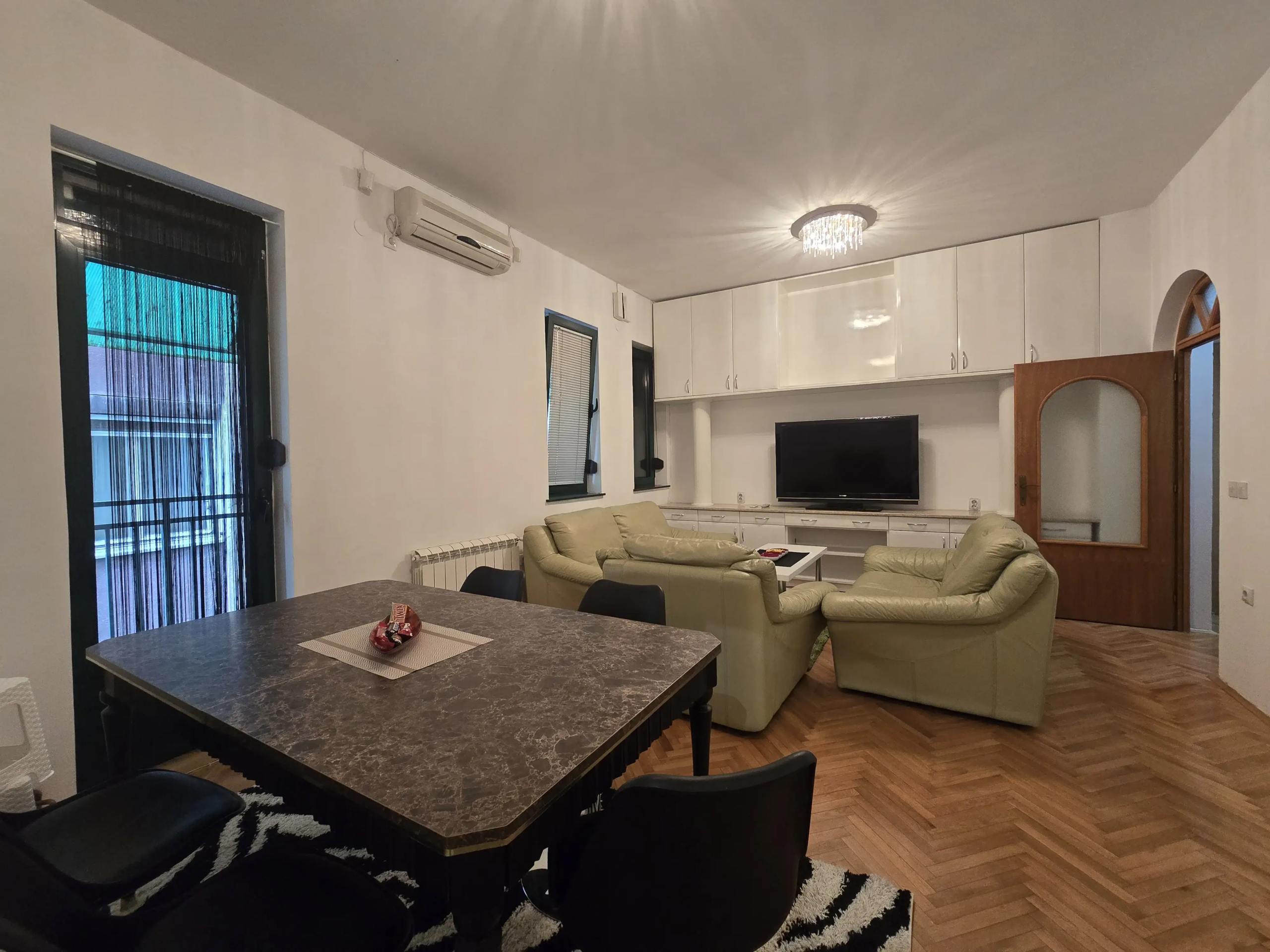 Dnevna soba sa ugaonom garniturom, tv, trpezarijski sto, izlaz na terasu